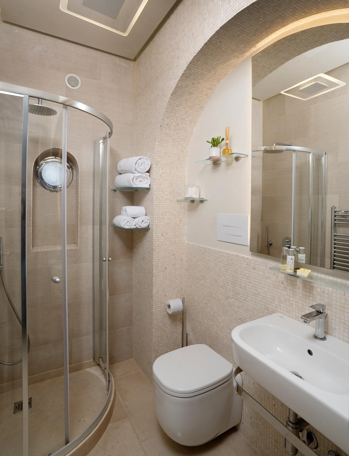 Il secondo bagno con specchio ad arco, mosaico beige e doccia curva in cristallo