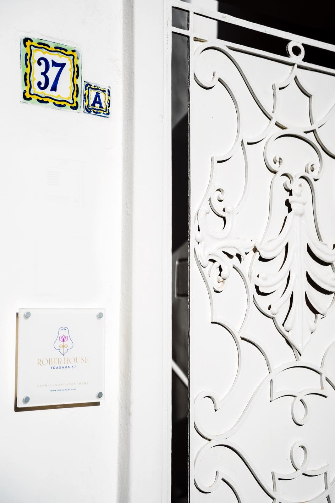 L'ingresso di Rober House: cancello in ferro battuto bianco, civico 37 in maioliche di Capri e targa col logo