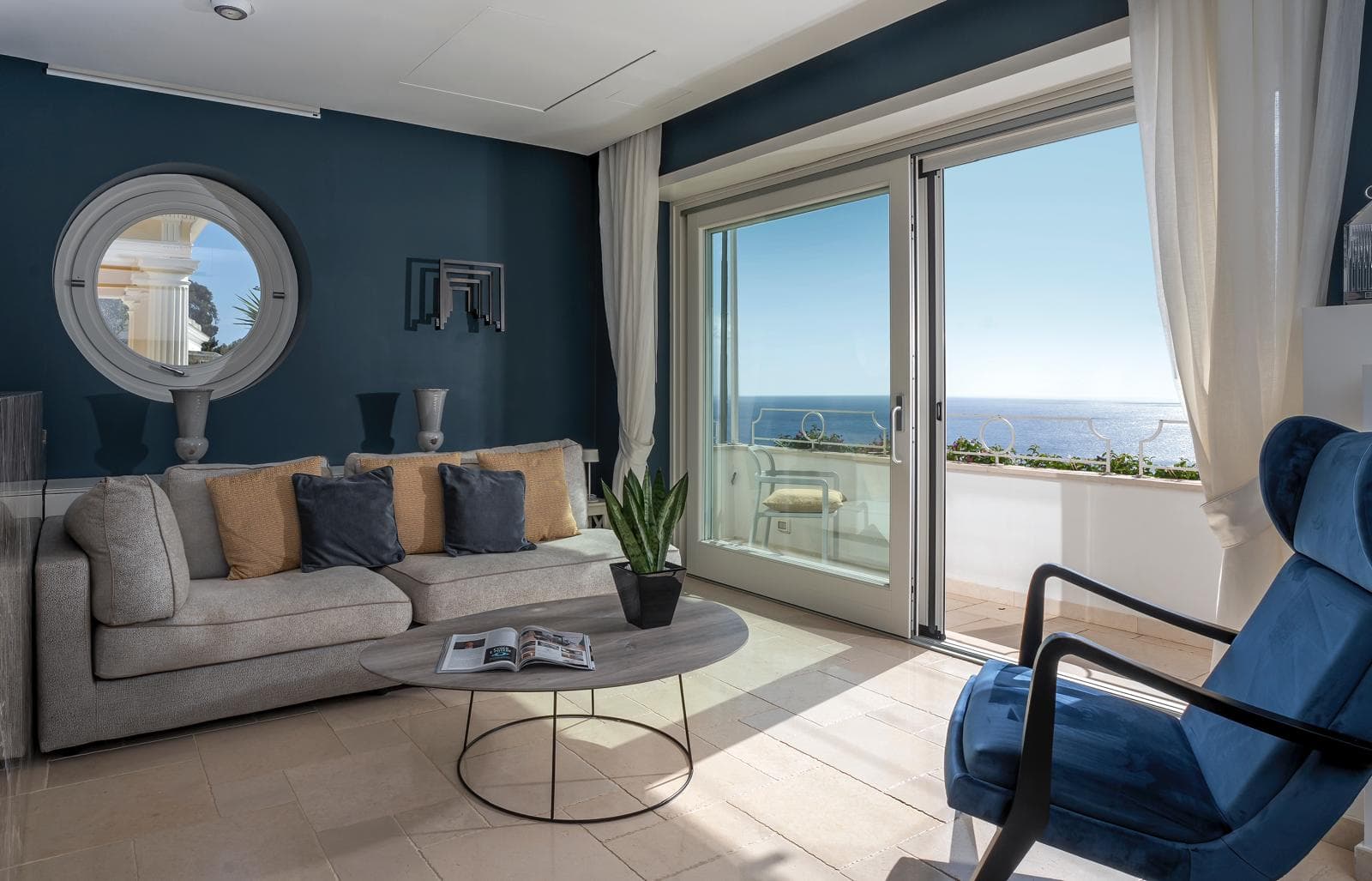Il salone blu Capri con divano, poltrona velluto e vista mare attraverso le portefinestre